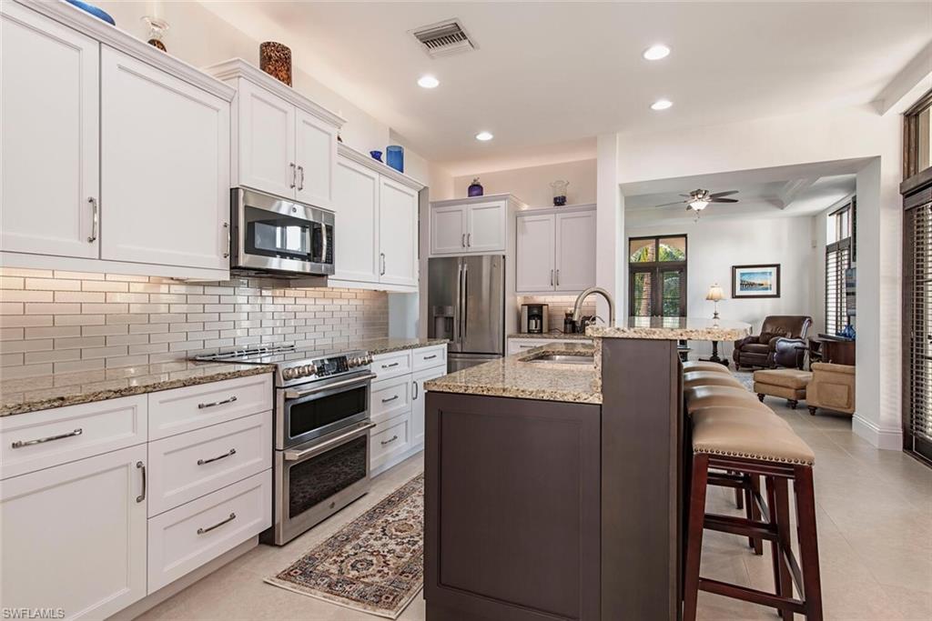 1012 7th Street South, Unit B2 Naples, FL 34102 - Photo 7 of 17 a kitchen with kitchen island granite countertop lots of counter top space and stainless steel appliances