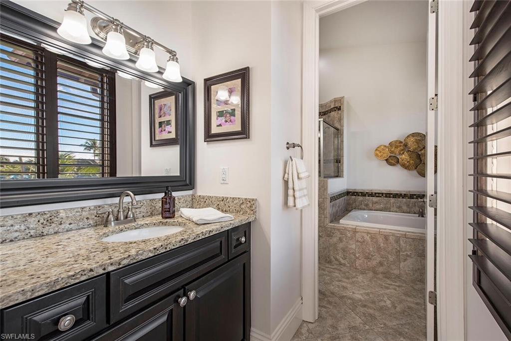1012 7th Street South, Unit B2 Naples, FL 34102 - Photo 9 of 17 a en suite bathroom with a granite countertop sink a mirror and shower