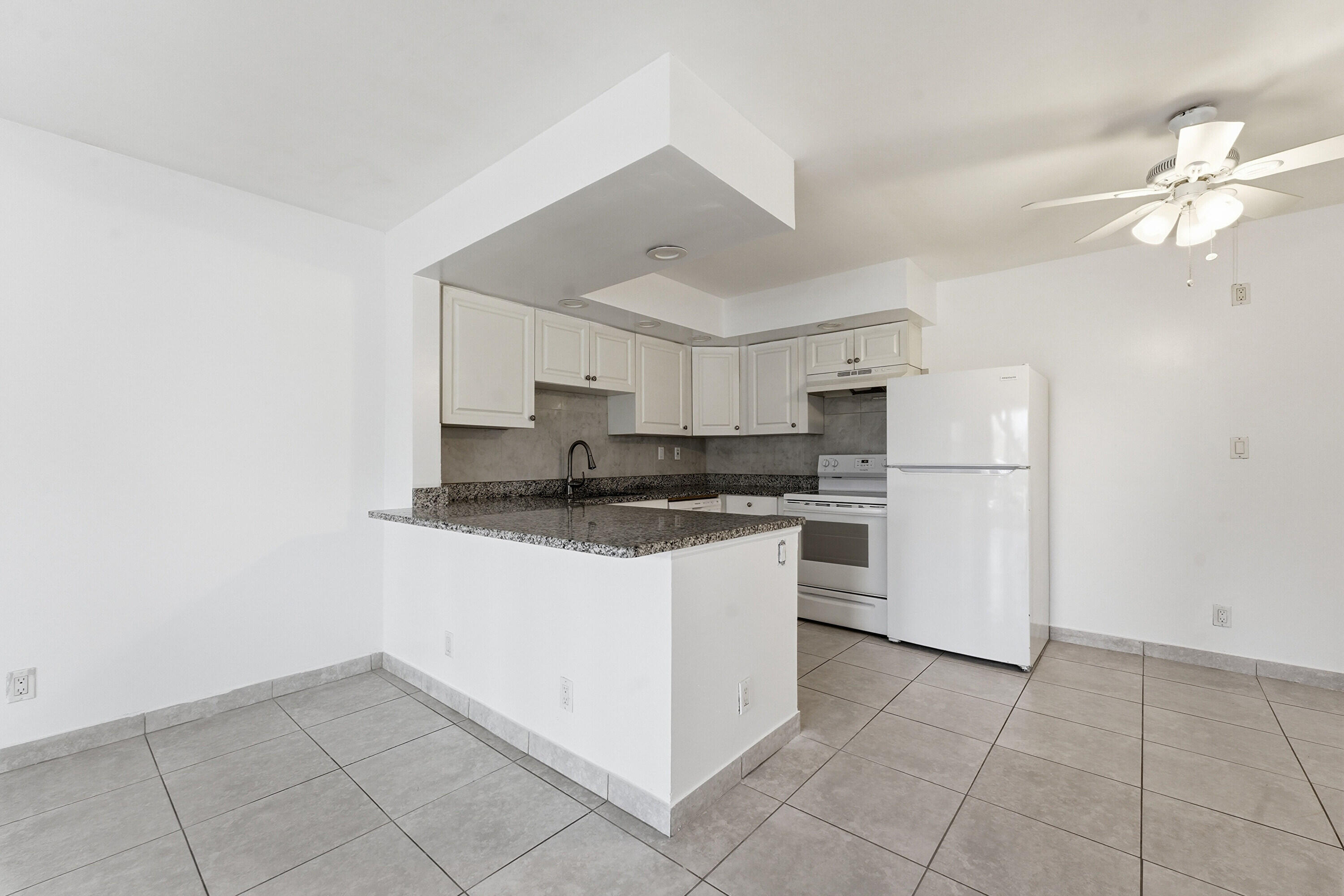 2671 Riverside Drive, Unit 1 Coral Springs, FL 33065 - Photo 7 of 25 a kitchen with kitchen island granite countertop white cabinets white stainless steel appliances with a sink and dishwasher