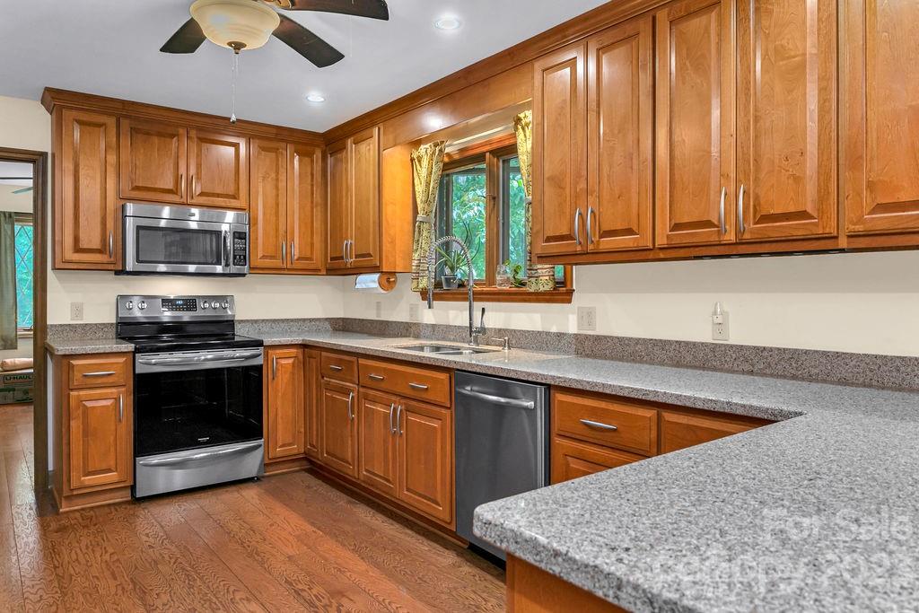 330 Beau Valley Road Tryon, NC 28782 - Photo 13 of 42 a kitchen with stainless steel appliances granite countertop wooden cabinets a sink a stove and a microwave