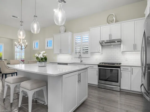 a kitchen with stainless steel appliances granite countertop a sink a stove a refrigerator and island with wooden floor