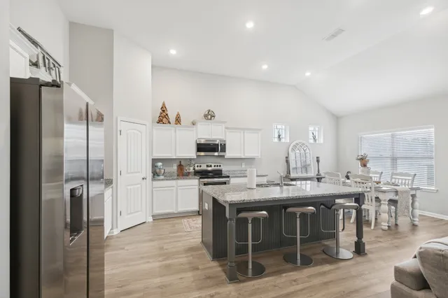 a kitchen with stainless steel appliances granite countertop a table chairs stove a refrigerator and a sink