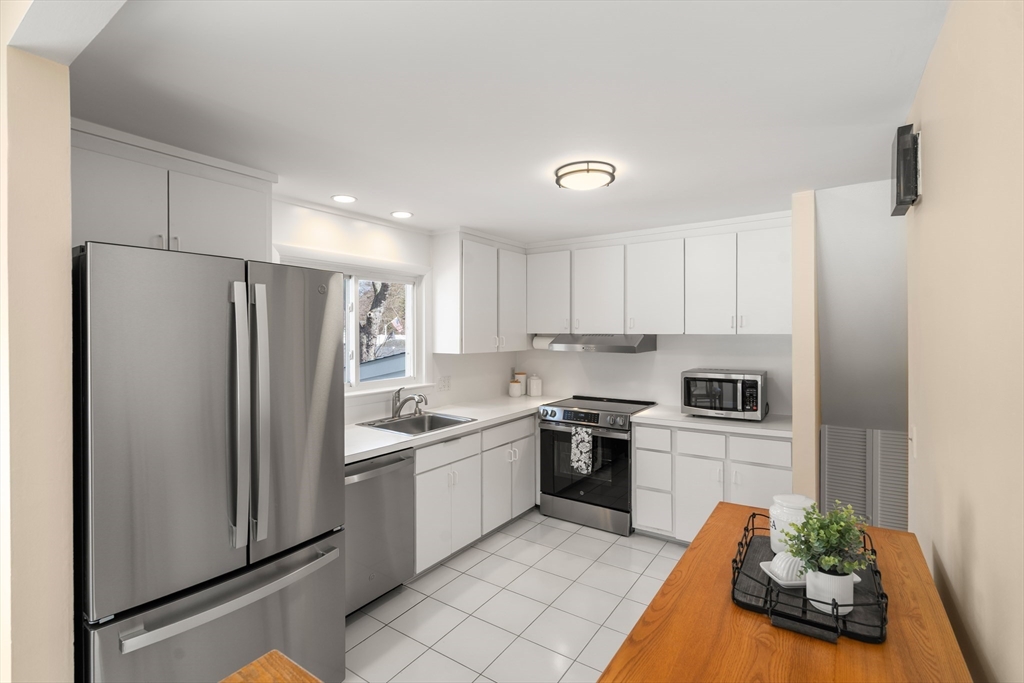 13 Berkeley Road Framingham, MA 01701 - Photo 8 of 32 a kitchen with white cabinets and stainless steel appliances