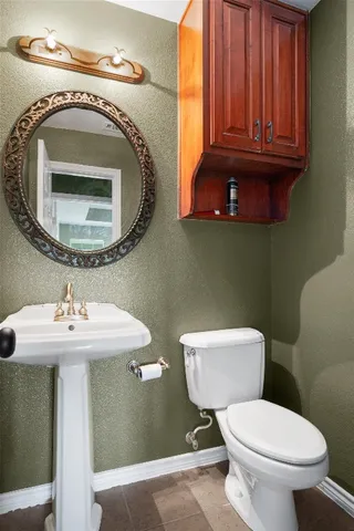 a bathroom with a toilet a sink and mirror