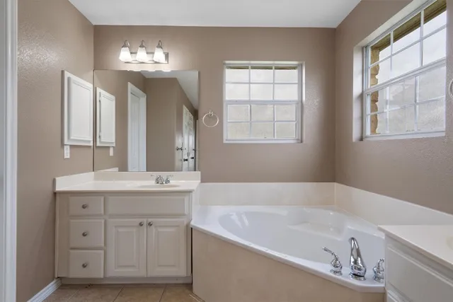 a bathroom with a tub a sink and mirror
