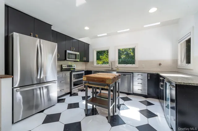 a kitchen with stainless steel appliances granite countertop a refrigerator a stove a sink a dining table and chairs