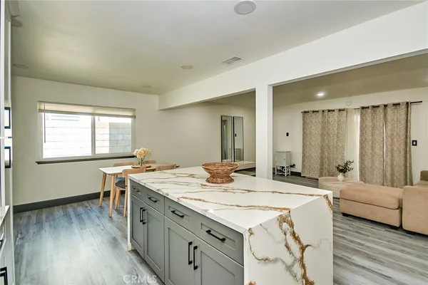 a dining hall with stainless steel appliances granite countertop a stove a sink dishwasher and microwave with wooden floor
