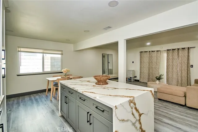 a dining hall with stainless steel appliances granite countertop a stove a sink dishwasher and microwave with wooden floor