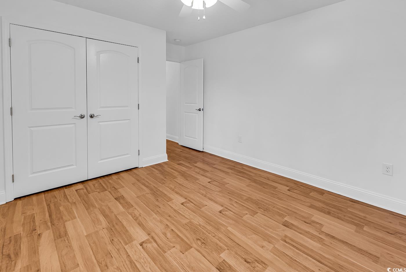 327-a&b Sparrow Drive Surfside Beach, SC 29575 - Photo 29 of 33 Unfurnished bedroom with light wood-style floors, a ceiling fan, and a closet