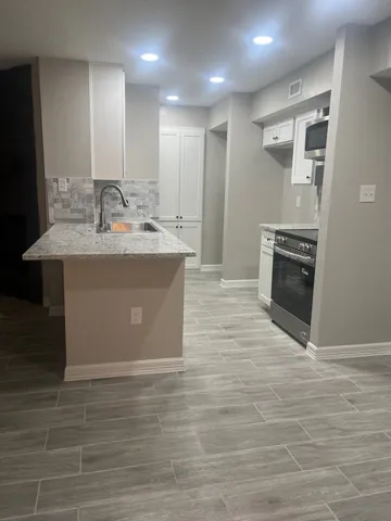 a view living room with stainless steel appliances wooden floor and chandelier