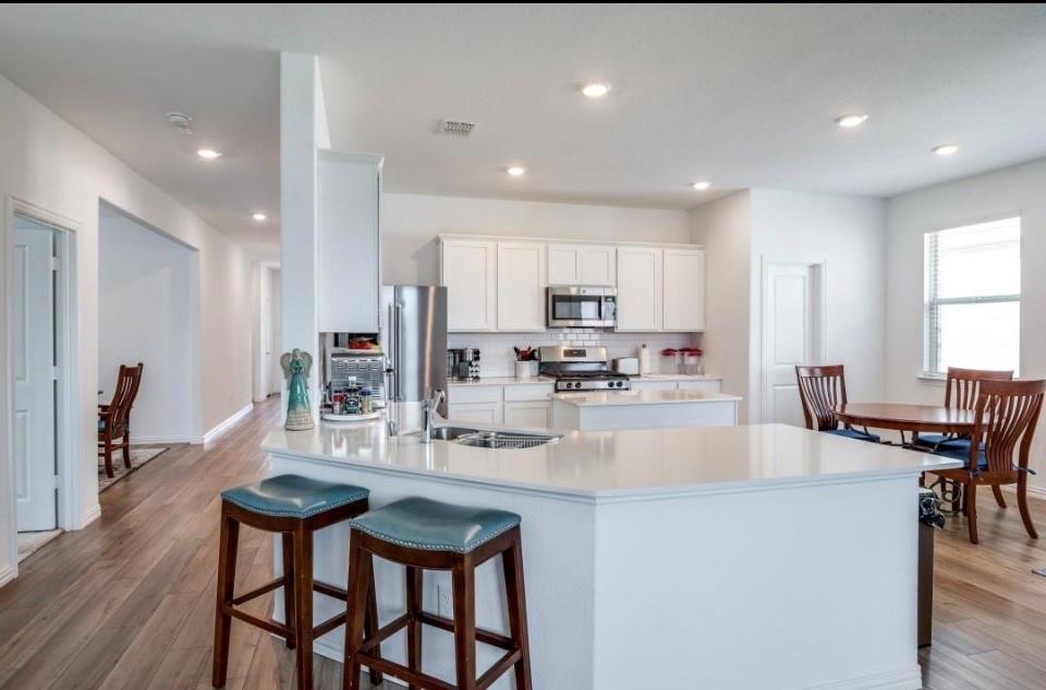 8424 Gray Squirrel Ln. McKinney, TX 75071 - Photo 5 of 22 a kitchen with stainless steel appliances kitchen island granite countertop a dining table chairs refrigerator and microwave