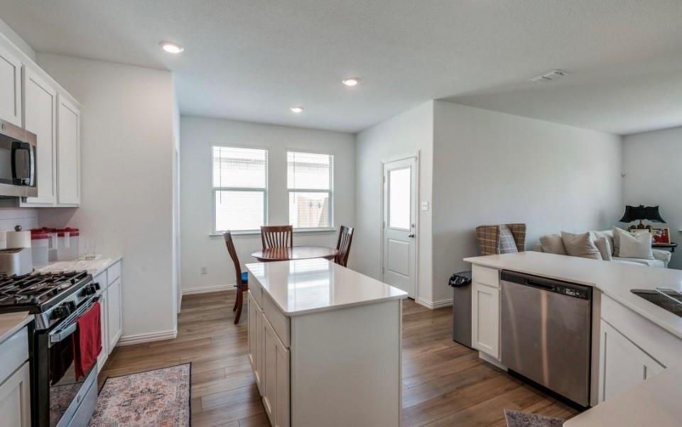 8424 Gray Squirrel Ln. McKinney, TX 75071 - Photo 22 of 22 a open kitchen with stainless steel appliances granite countertop a stove top oven a sink dishwasher and white cabinets with wooden floor