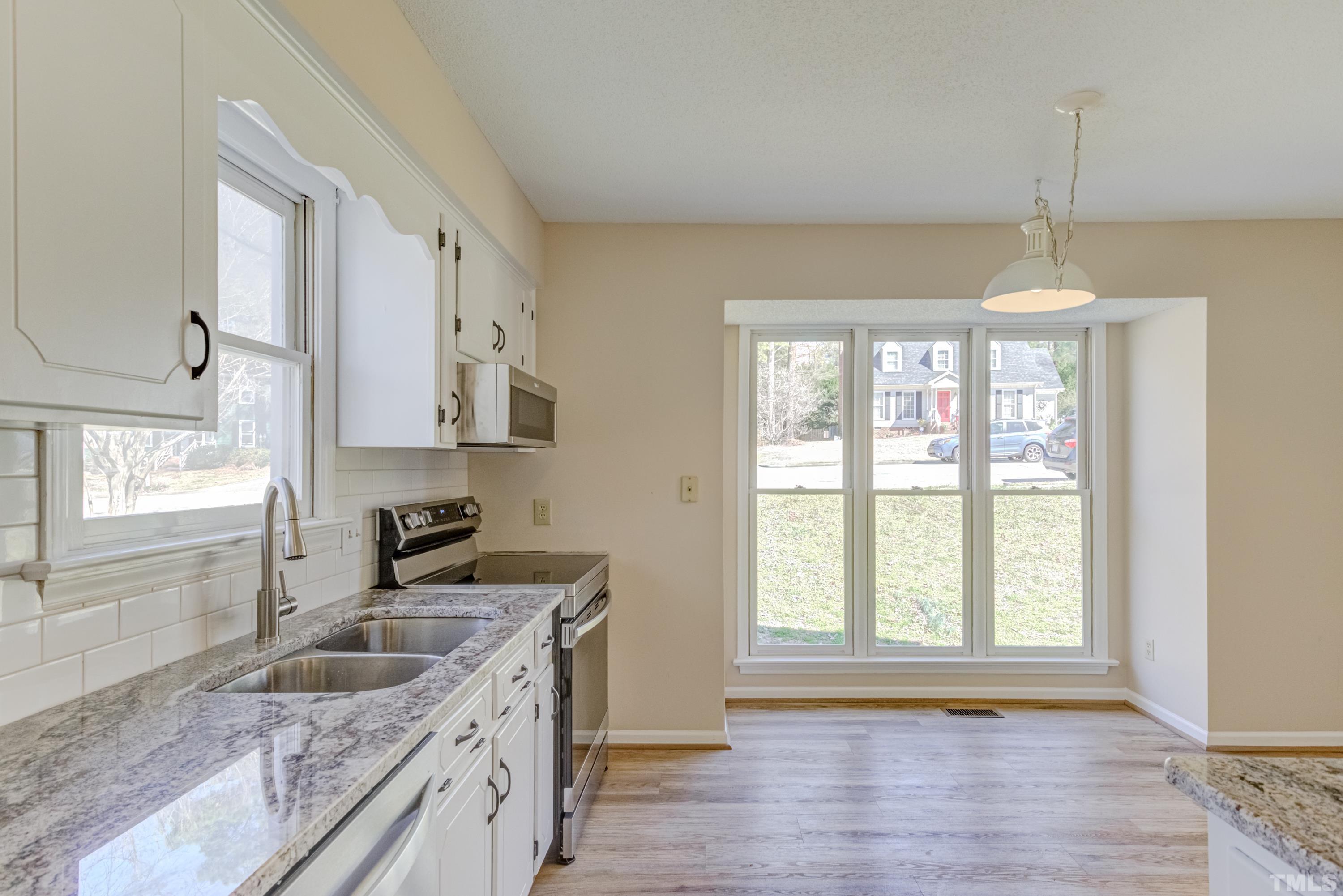 7307 Wilderness Road Raleigh, NC 27613 - Photo 8 of 14 a kitchen with granite countertop a sink a counter space appliances and cabinets