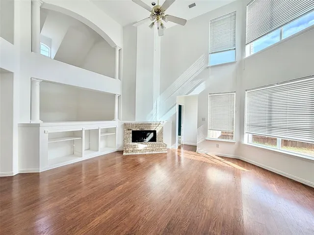 a view of a livingroom with wooden floor a ceiling fan and windows