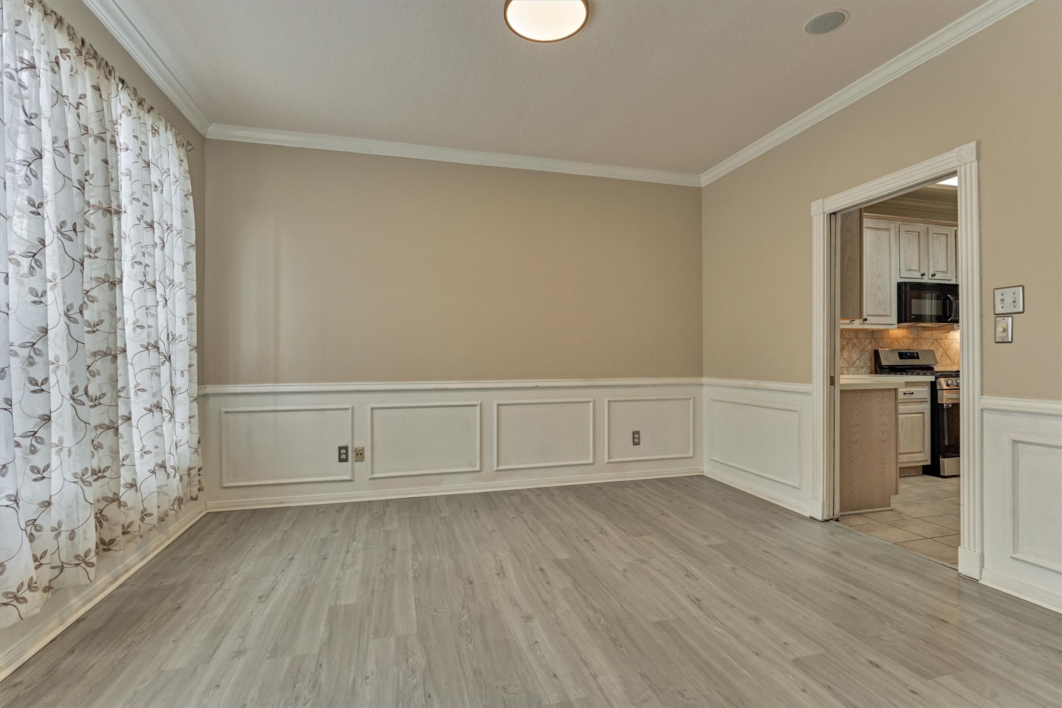 14420 Walters Road, Unit 26 Houston, TX 77014 - Photo 21 of 45 Bright formal dining room with elegant wainscoting, light wood flooring, and floral curtains. It opens to the kitchen with brand new appliances.