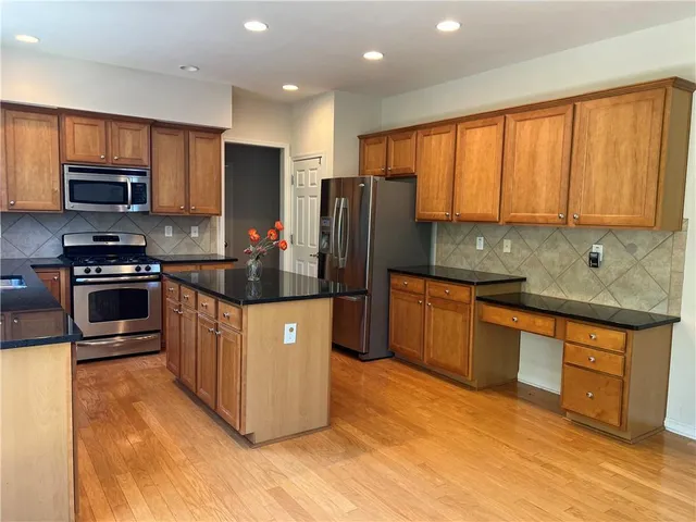 a kitchen with stainless steel appliances granite countertop a refrigerator a stove top oven a sink and dishwasher