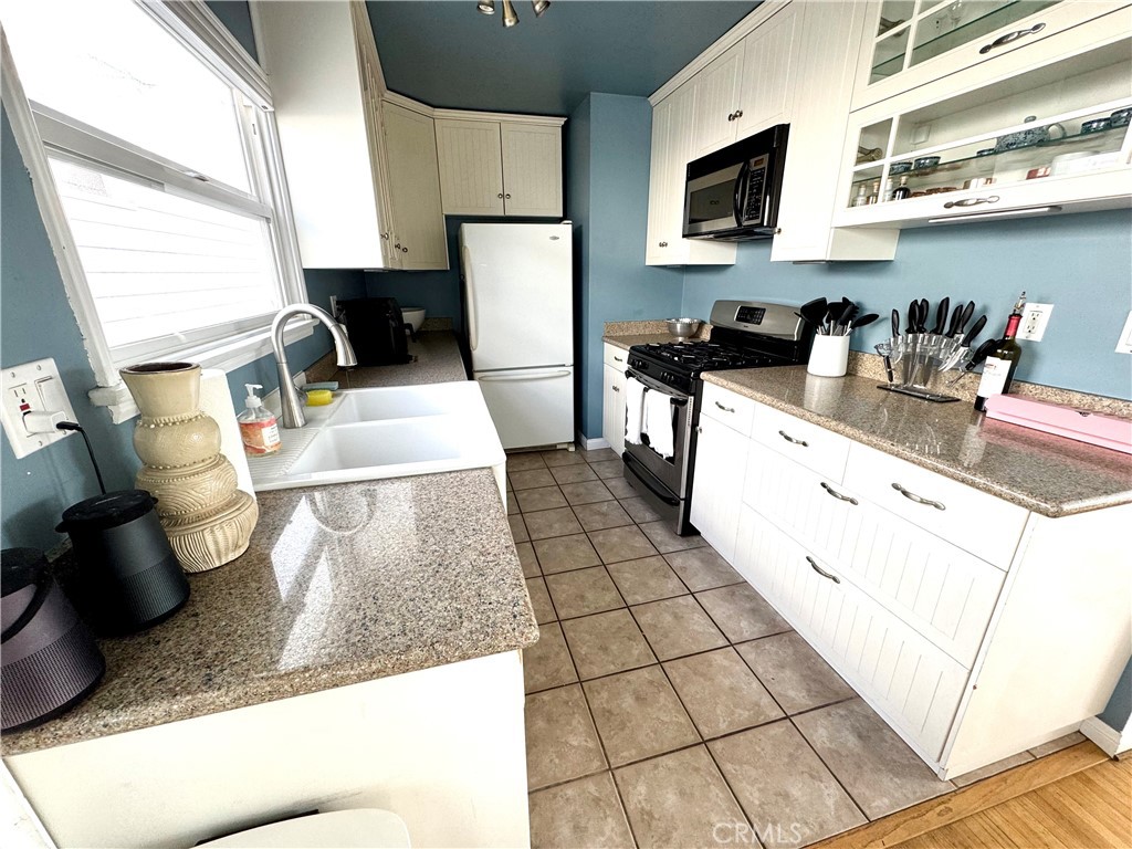 504 36th Street, Unit 1/2 Newport Beach, CA 92663 - Photo 6 of 15 a kitchen with stainless steel appliances kitchen island granite countertop a sink dishwasher a stove a microwave oven and white cabinets with wooden floor