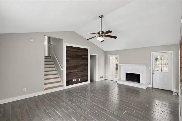 a view of an empty room with wooden floor fireplace and a window