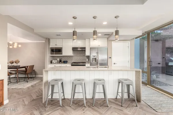 a large white kitchen with lots of counter space dining table and stainless steel appliances