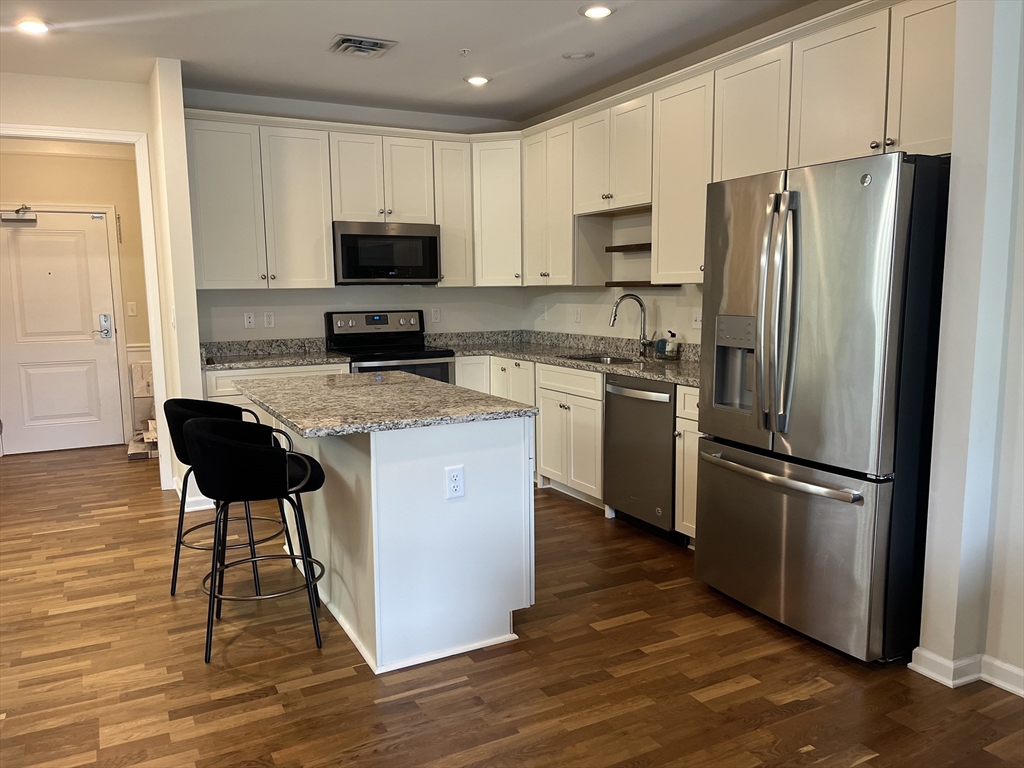 110 Trotter Road, Unit 308 Weymouth, MA 02190 - Photo 2 of 11 a kitchen with stainless steel appliances granite countertop a refrigerator stove microwave and sink