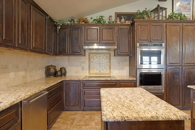 a kitchen with granite countertop wooden cabinets and stainless steel appliances