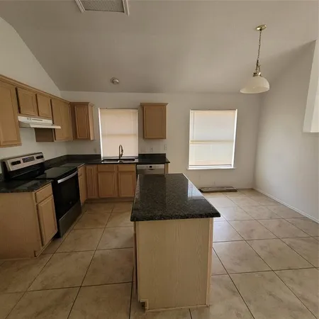 a kitchen with granite countertop a sink a stove and cabinets