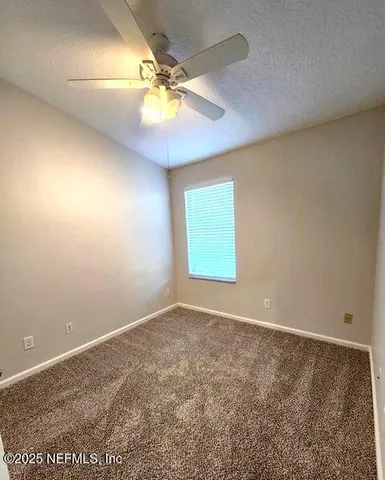 an empty room with a ceiling fan and a window