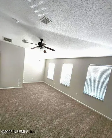 an empty room with windows and fan