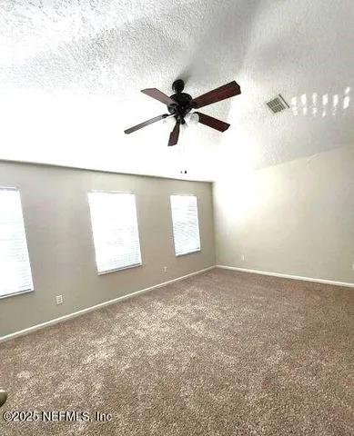 an empty room with windows and fan