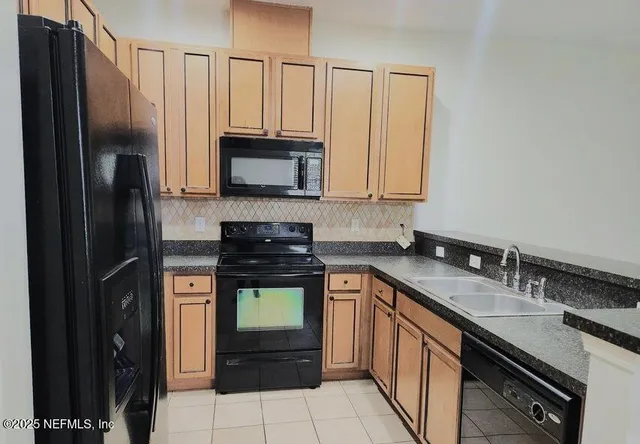 a kitchen with stainless steel appliances granite countertop a refrigerator a stove a sink and a microwave