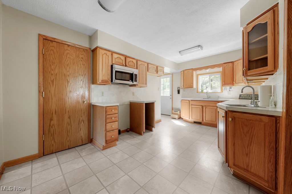 1702 Far View Road Akron, OH 44312 - Photo 10 of 49 Kitchen featuring light countertops, stainless steel microwave, glass insert cabinets, and decorative backsplash