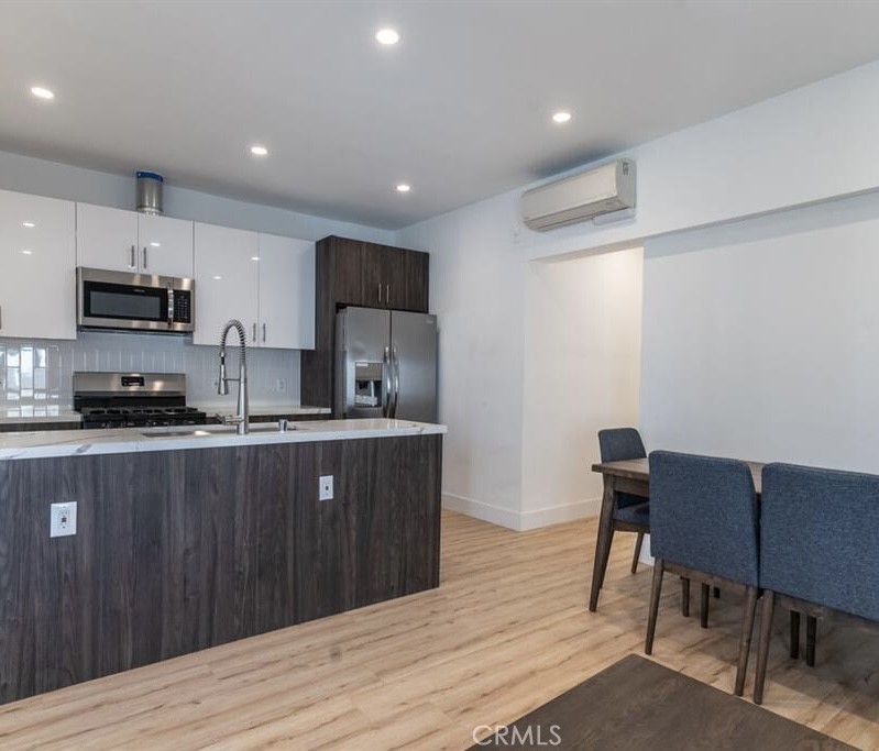 a kitchen with stainless steel appliances granite countertop a sink dishwasher a stove a refrigerator a dining table and chairs