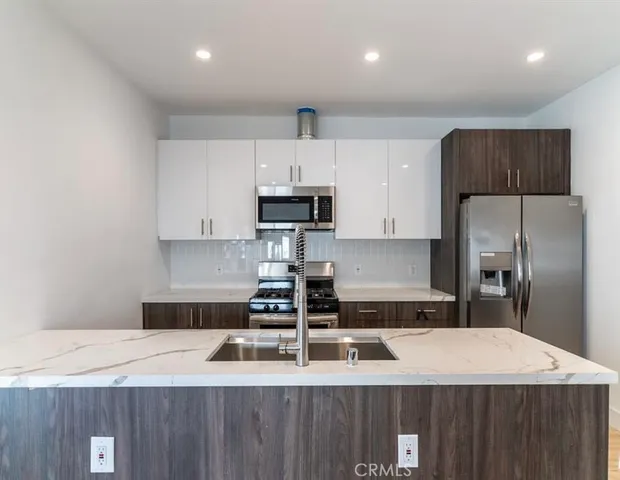 a kitchen with kitchen island a counter top a stove a refrigerator and a sink