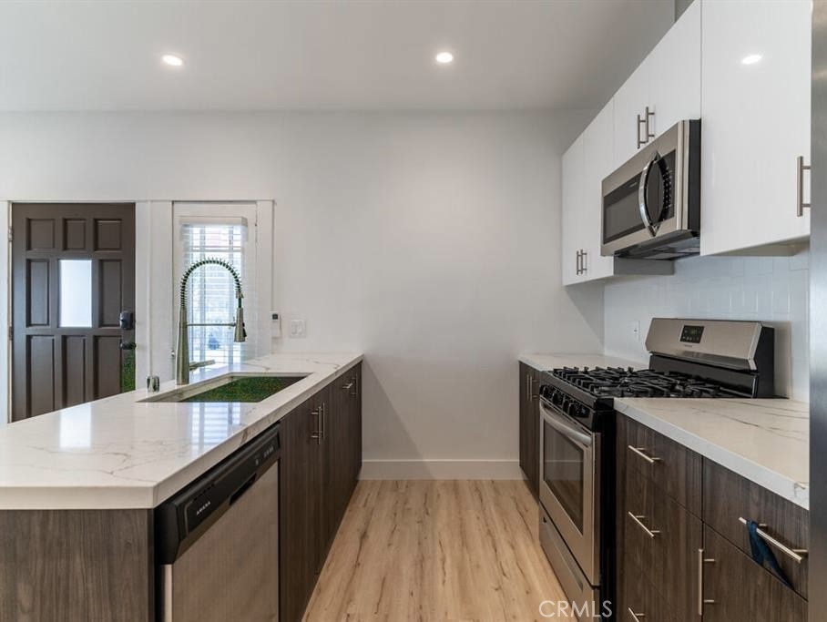 1213 West 24th Street Los Angeles, CA 90007 - Photo 3 of 11 a kitchen with stainless steel appliances granite countertop a sink a stove top oven and wooden floor