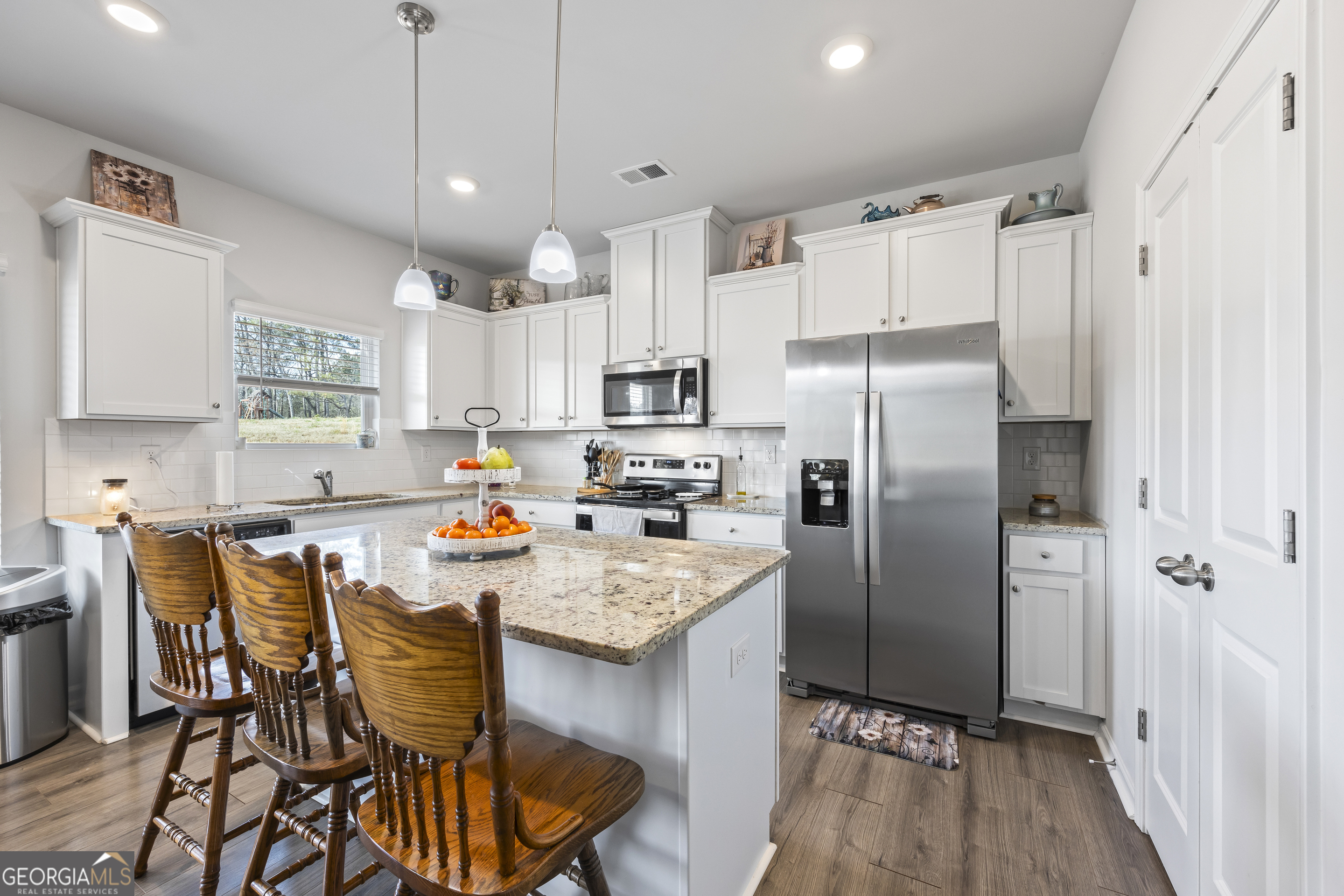 1064 Emmas Path Monroe, GA 30656 - Photo 19 of 55 a kitchen with stainless steel appliances a refrigerator a stove a sink a dining table and chairs with wooden floor
