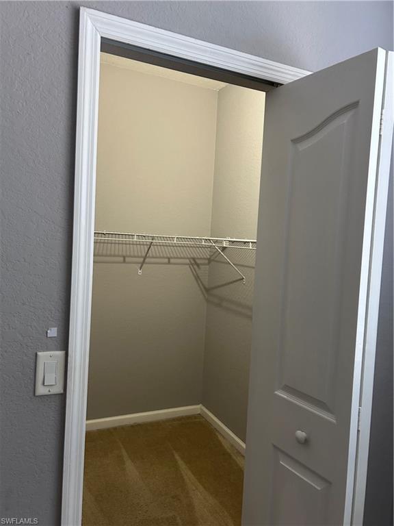 12975 Positano Circle, Unit 307 Naples, FL 34105 - Photo 2 of 6 Walk in closet featuring dark colored carpet
