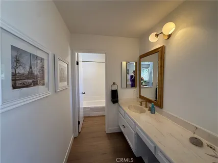 a bathroom with a double vanity sink and mirror with bathtub