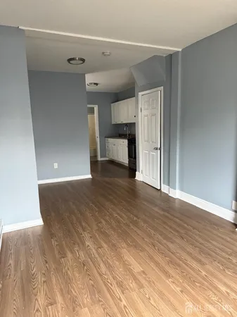 a view of a big room with wooden floor and kitchen view