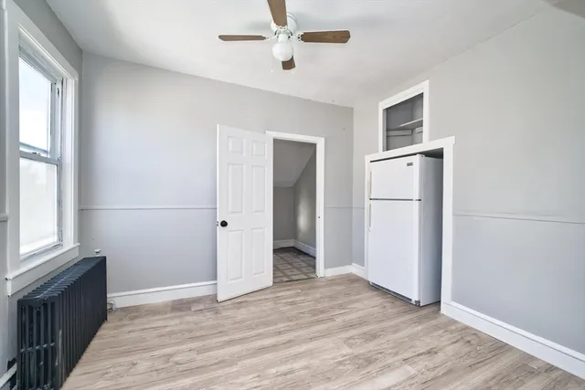 a view of an empty room with a window and wooden floor