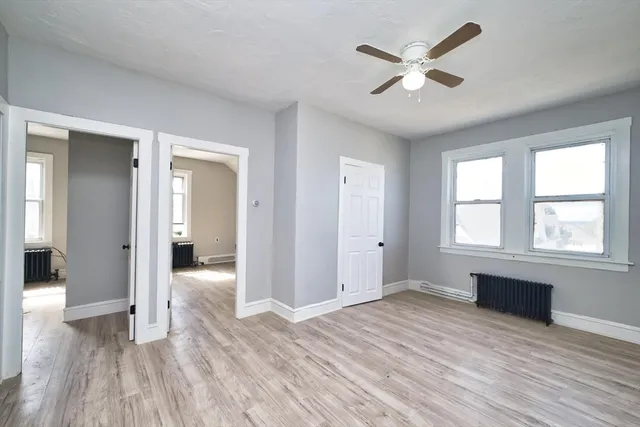 a view of empty room with wooden floor and fan