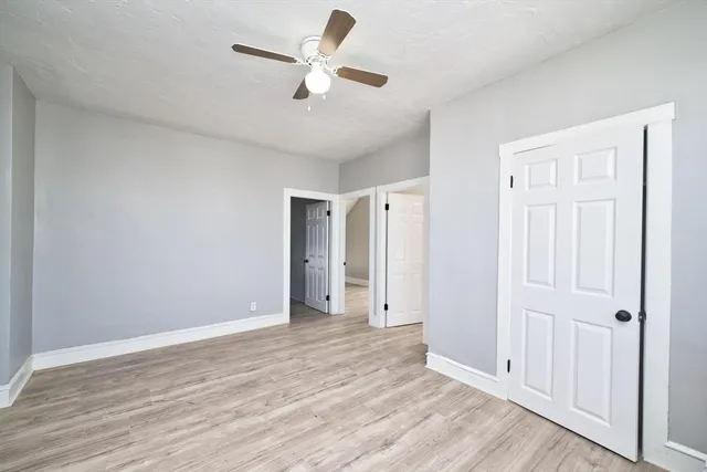 an empty room with wooden floor and ceiling fan