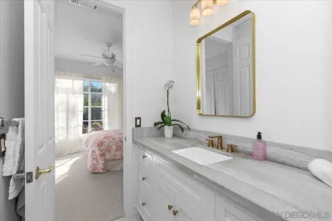 a en suite bathroom with a granite countertop sink and a mirror
