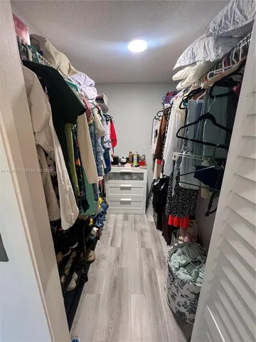 a view of walk in closet with clothes and shoes