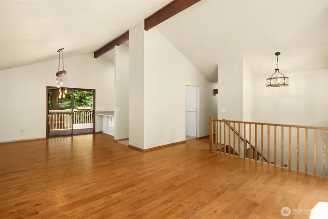 a view of an empty room with window and wooden floor