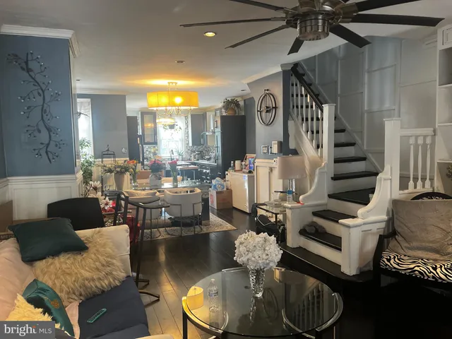 a living room with couches chairs and kitchen view with wooden floor