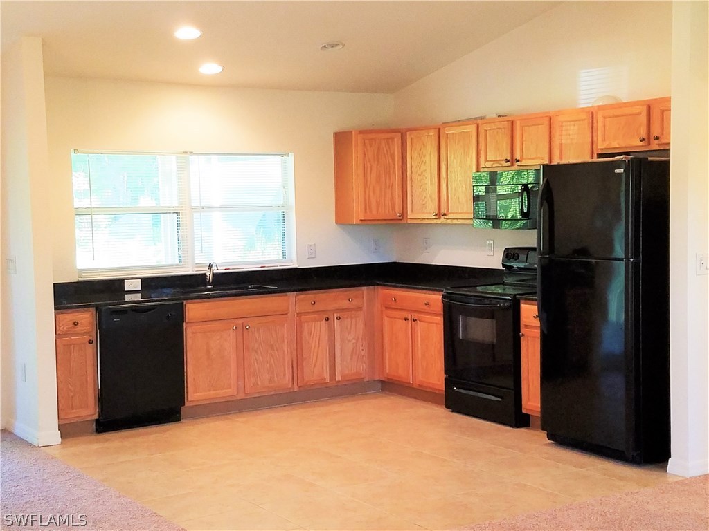 2910 25th Street West Lehigh Acres, FL 33971 - Photo 1 of 15 a kitchen with granite countertop a refrigerator and a sink