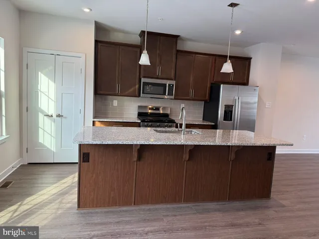 a kitchen with stainless steel appliances granite countertop a refrigerator a sink a stove a microwave and wooden floors