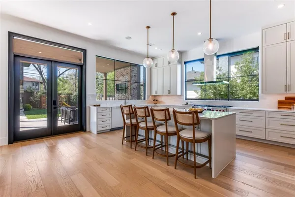 a kitchen with stainless steel appliances granite countertop a stove a refrigerator a sink a dining table and chairs with wooden floor