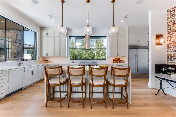 a open kitchen with stainless steel appliances granite countertop a stove a sink a dining table and chairs with wooden floor
