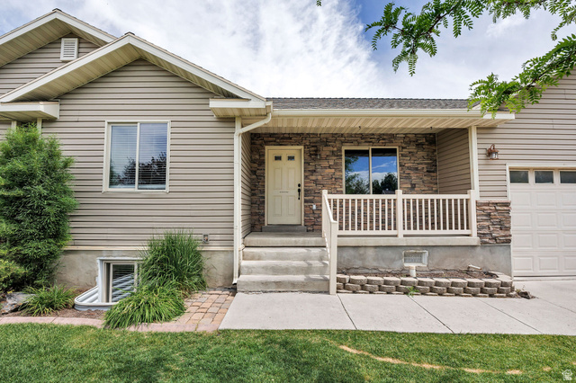 2912 South 1080th Street West Logan, UT 84321 - Photo 32 of 43 Front facade featuring beige siding, a stone veneer accent wall, and a covered porch with white railing